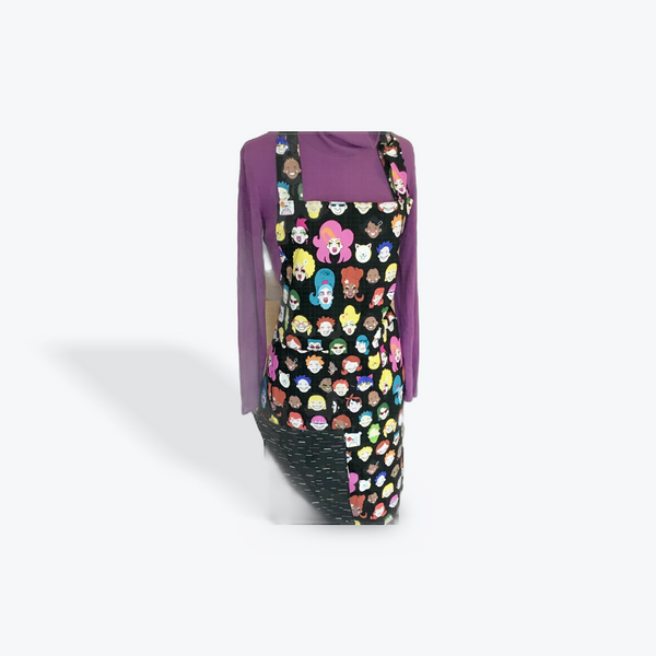 A reversible adult apron featuring a colorful pattern with character illustrations on one side and black multi color splatter on the othe with pockets on both sides.