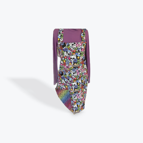 A reversible adult apron featuring a colorful pattern with skulls and the word queer on one side and a rainbow strip pattern on the reverse , with pockets on both sides.